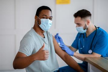Black man with thumbs up having a vaccine